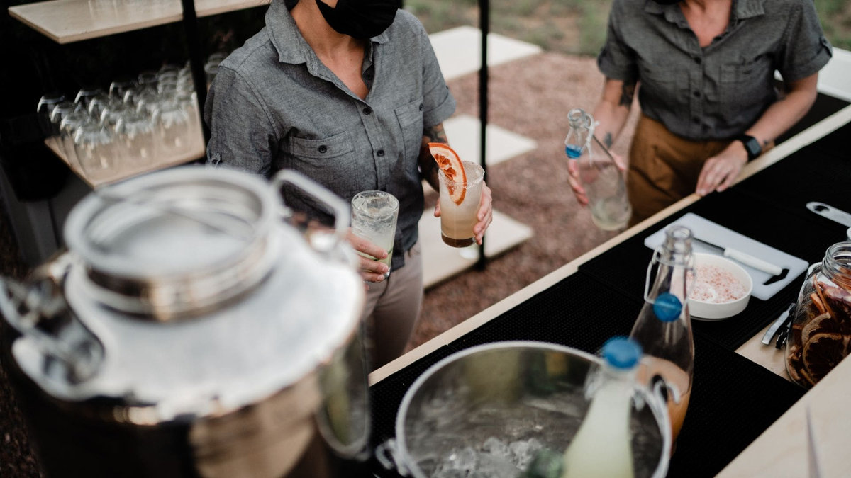 Two insured event bartenders serving cocktails at an outdoor bar setup